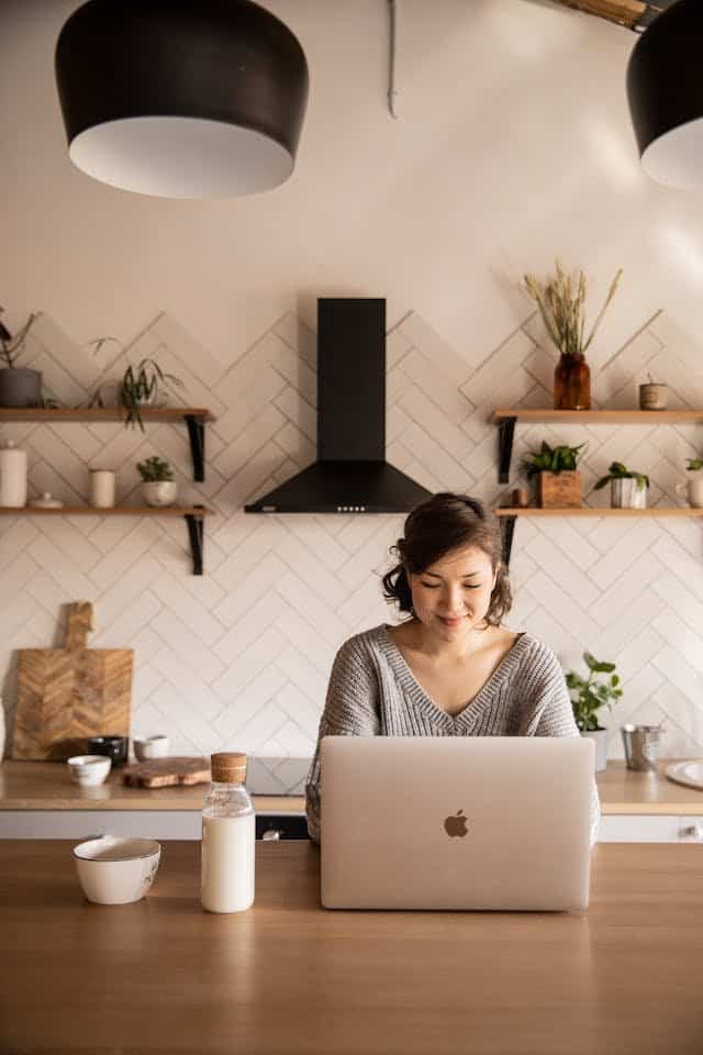 A woman working on her laptop in a kitchen.