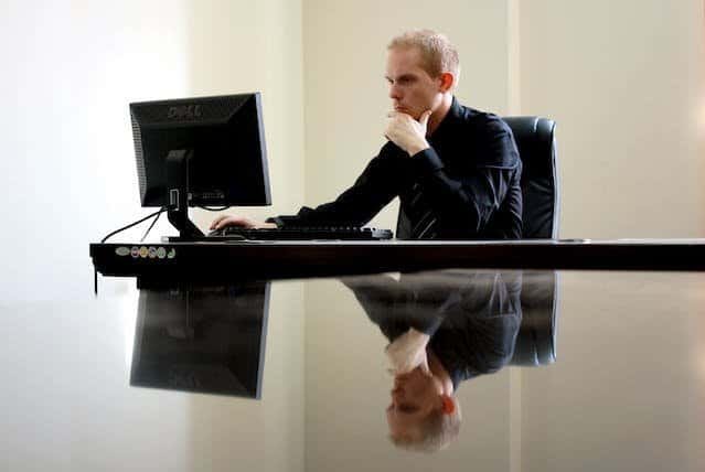 A man sitting at a desk with a computer in front of him.