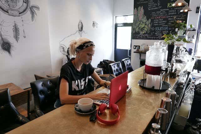 A woman working at a coffee shop with a laptop.